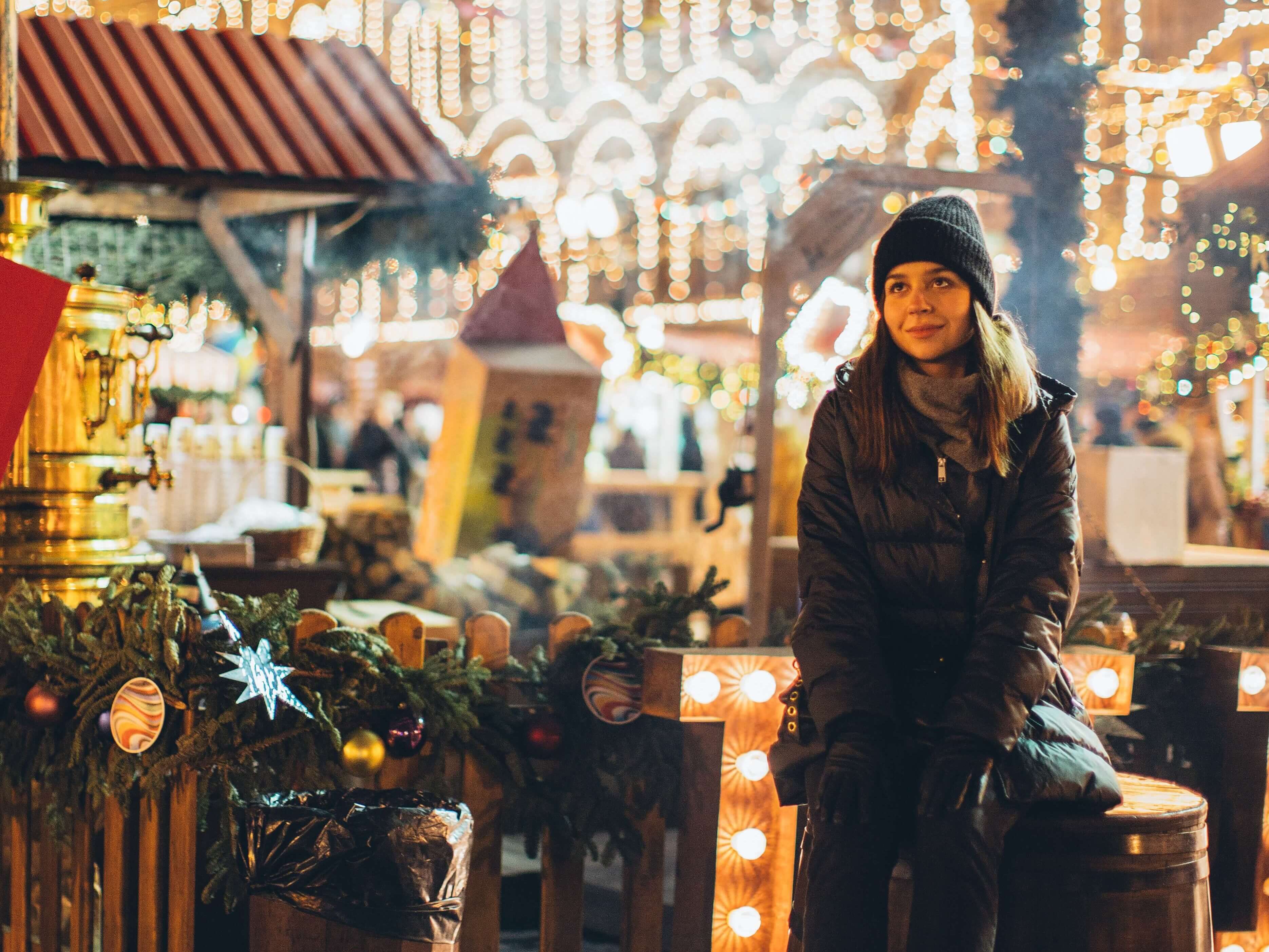 A woman having her picture taken in front of an xmas market